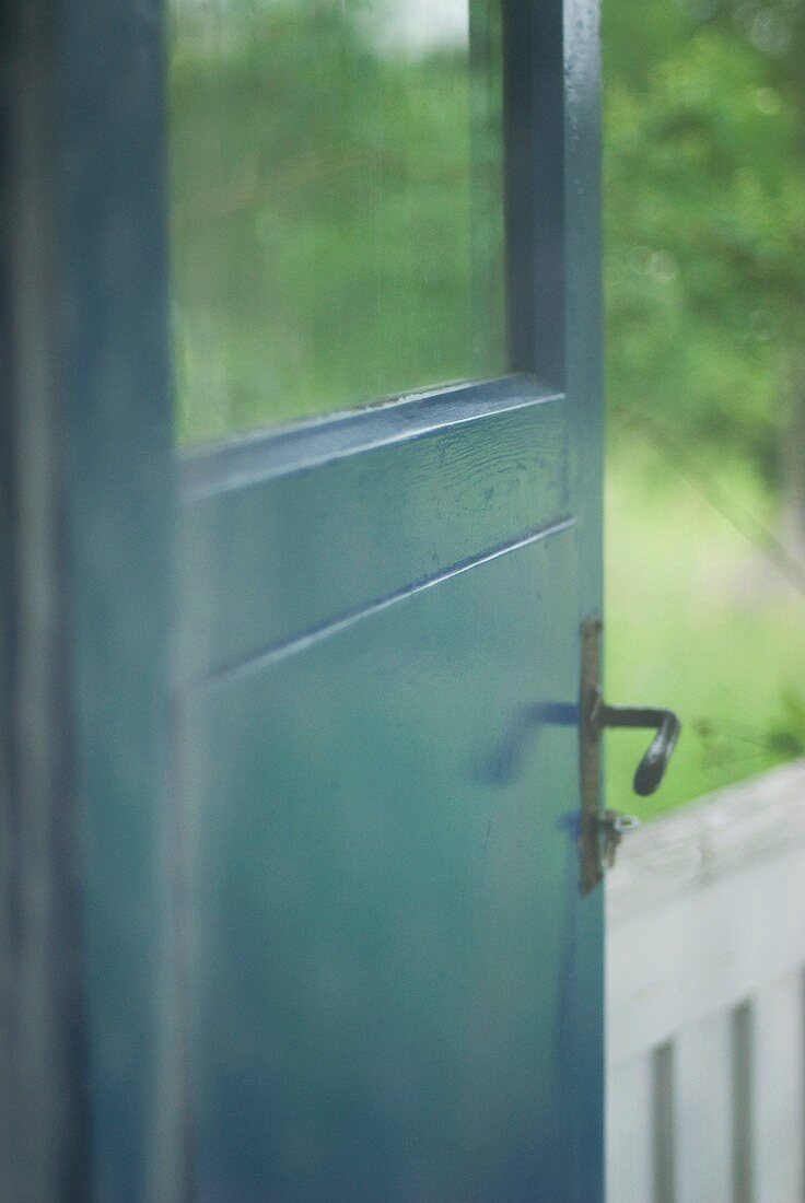 Petrolfarben lackierte Holztür mit Fensterscheibe und einfachem schwarzem Türbeschlag