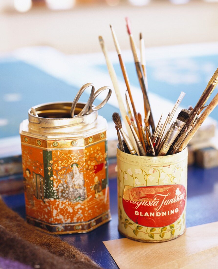 Paintbrushes and scissors in old tins