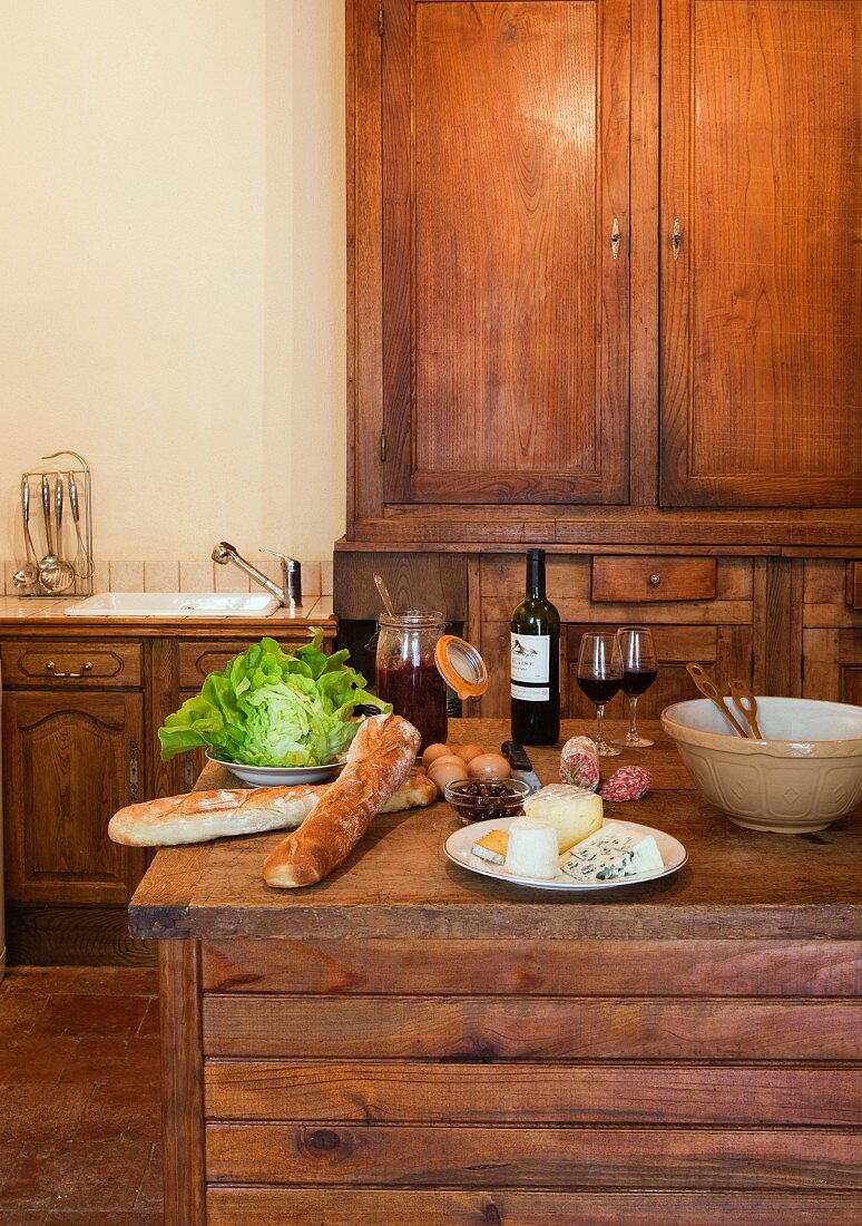 Wein, Baguette und Käse auf Theke in einer Holzküche