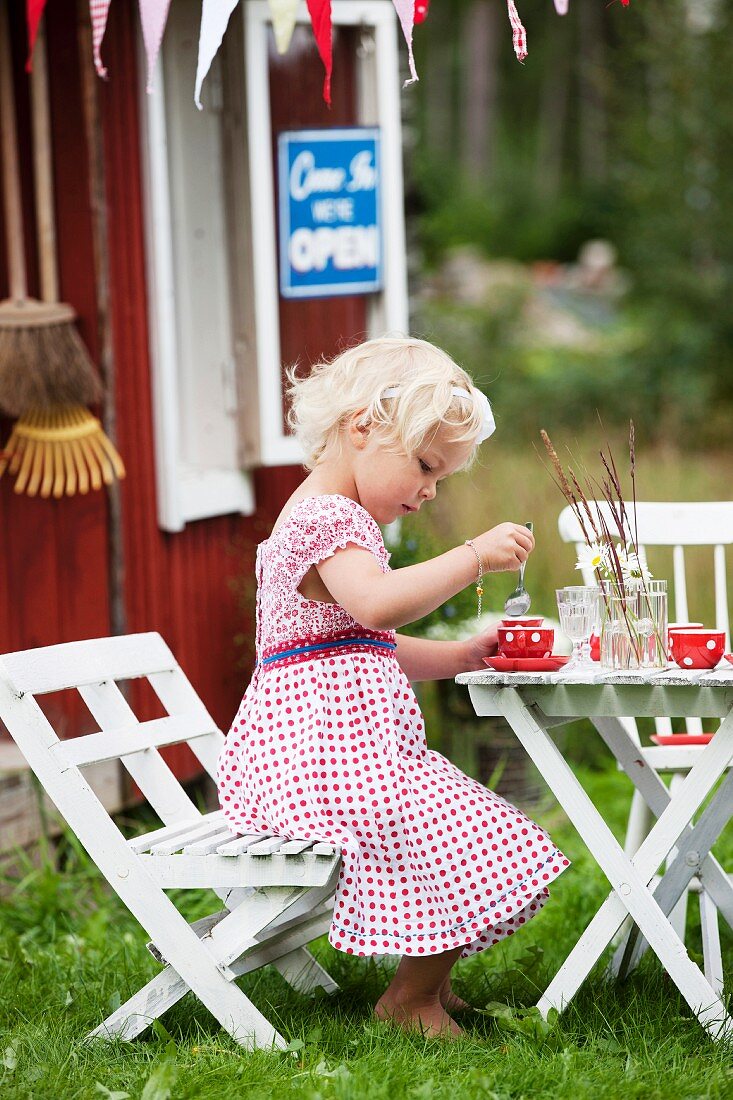 Kleines Mädchen beim Spiel an Kindertisch im Garten