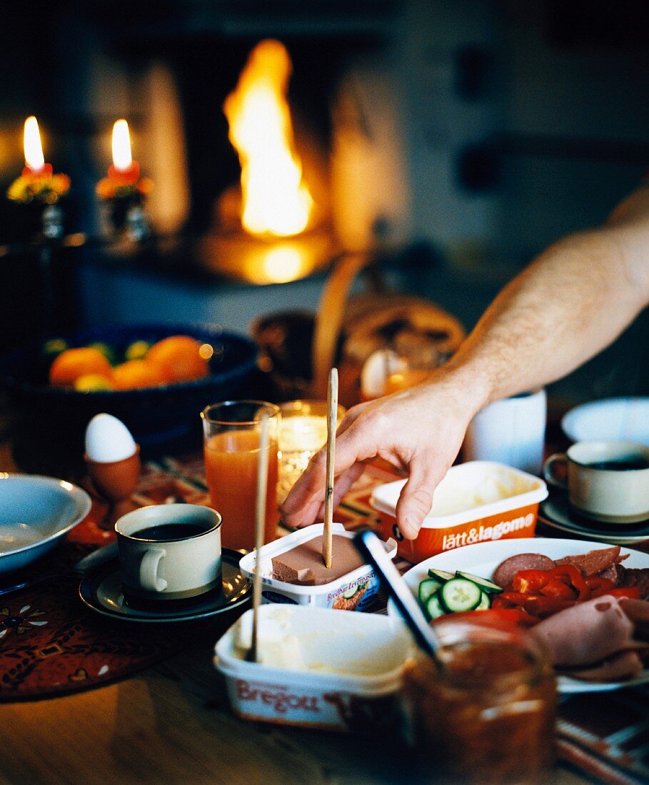 Gedeckter Frühstückstisch mit Kaminfeuer im Hintergrund