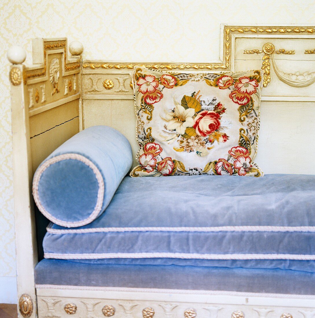 Head end of ornate, neoclassical wooden daybed with light blue velvet upholstery
