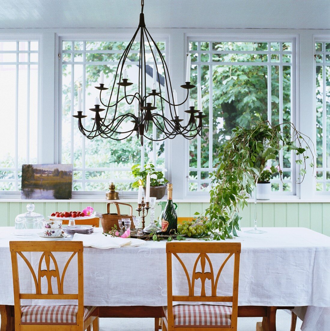 Biedermeier chairs at set table with white tablecloth in front of large window