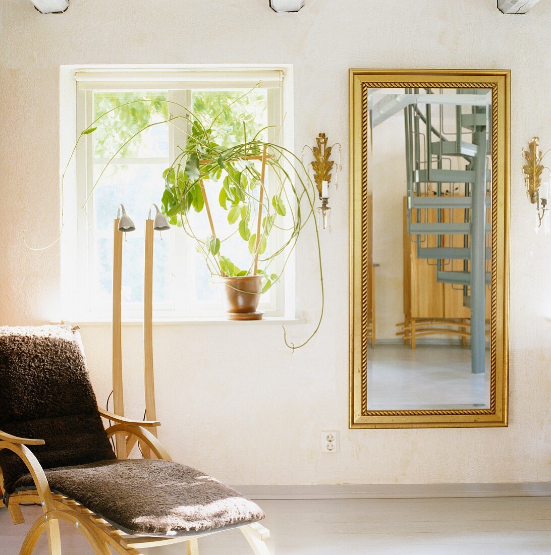 Skandinavische Bugholzliege und goldgerahmter Spiegel mit Reflektion einer Wendeltreppe