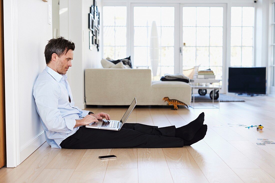 Mann mit Laptop auf dem Boden sitzend