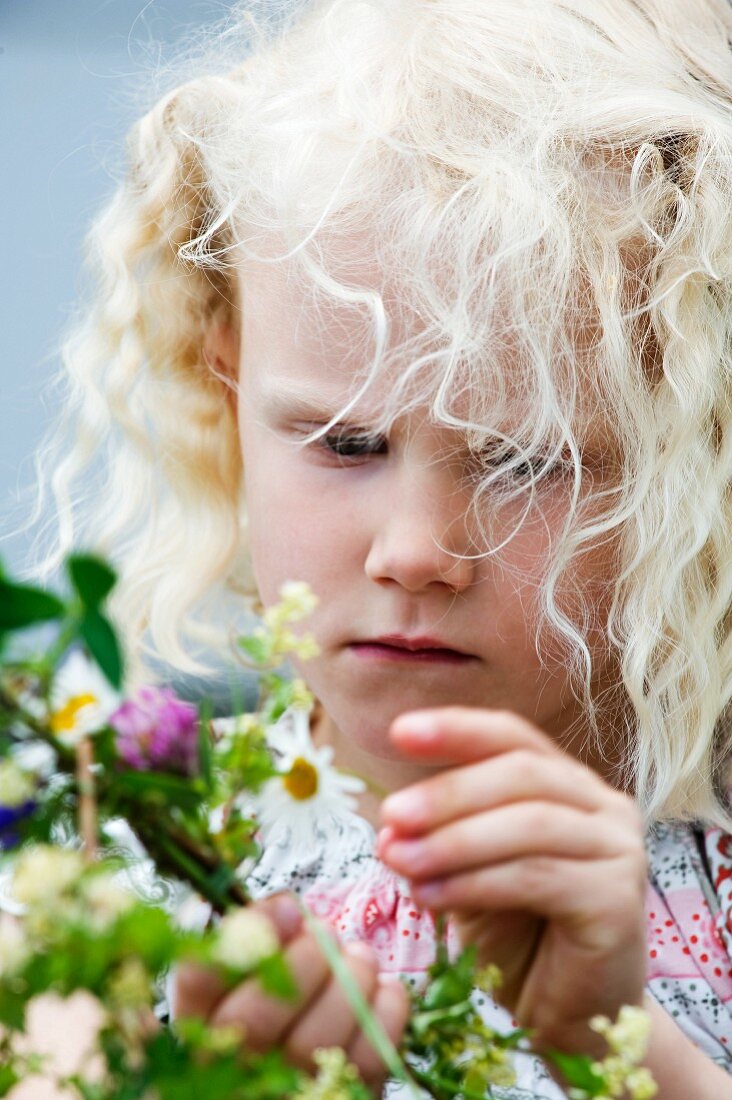 Blondes Mädchen hält Blumen in den Händen