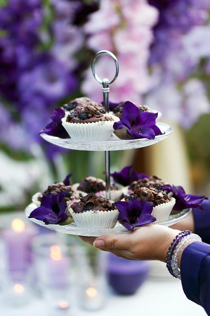 Etagere mit Schokoladenmuffins und lila Blüten