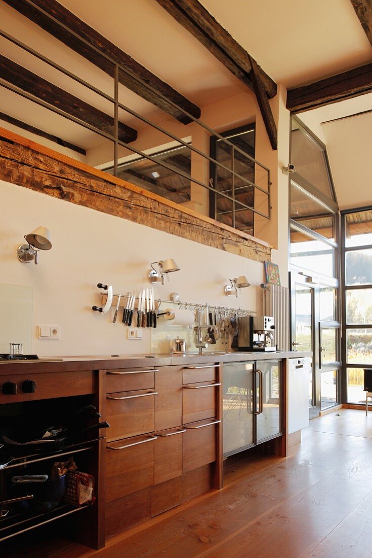 Modern kitchen counter below gallery with metal balustrade in renovated farmhouse