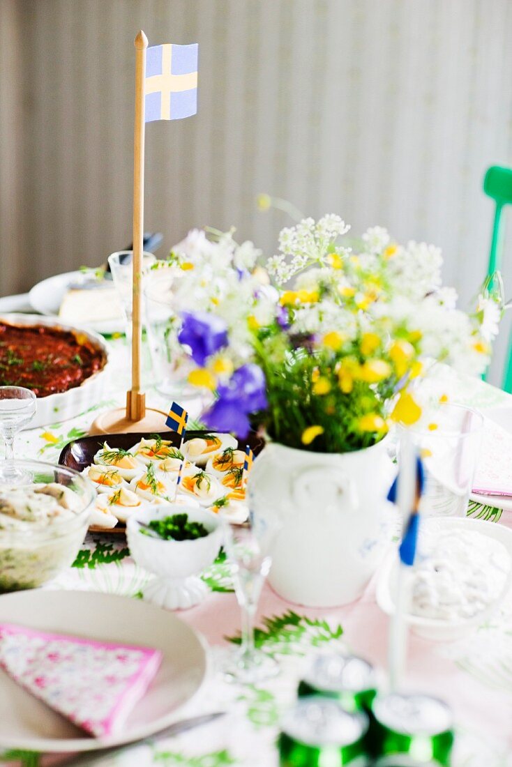 Gedeckter Tisch mit Blumenstrauss & schwedischer Flagge