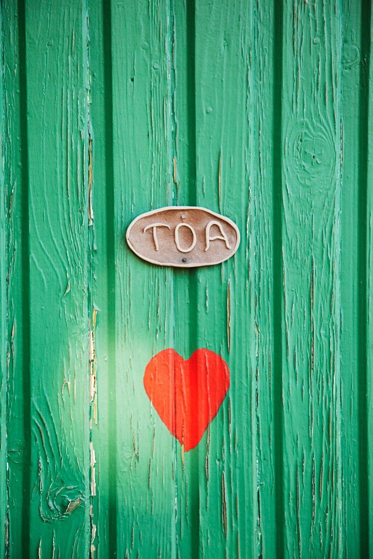 Rotes Herz auf grüner Tür eines Toilettenhäuschens