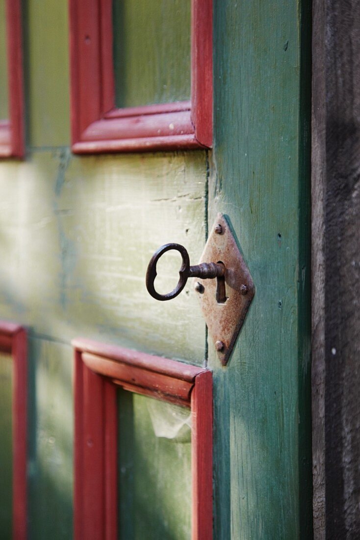 Old key in lock of wooden door (detail)