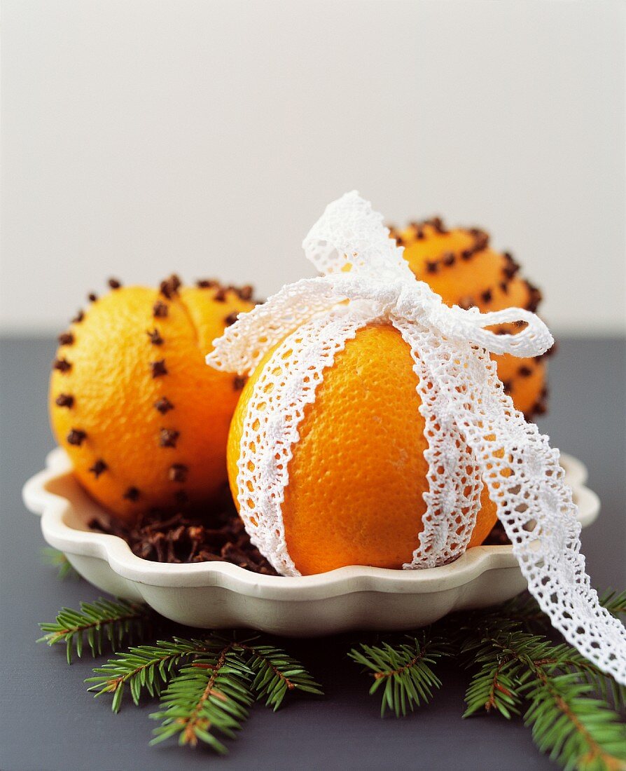 Orange pomanders stuck with cloves and decorated with lace ribbon