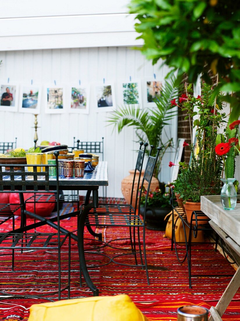 Raum mit weissen Holzwänden und einem roten Webteppich; auf dem Tisch orientalisches Essgeschirr