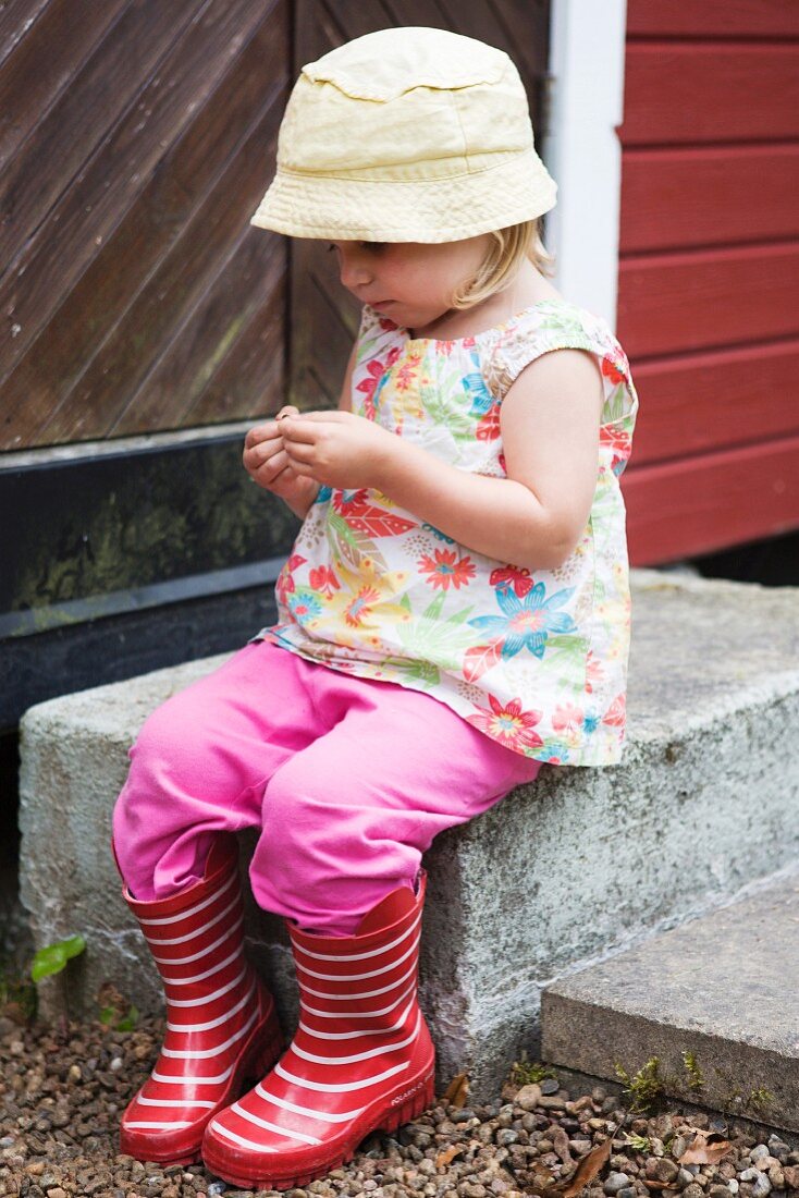 Kleines Mädchen auf einer Betonstufe sitzend