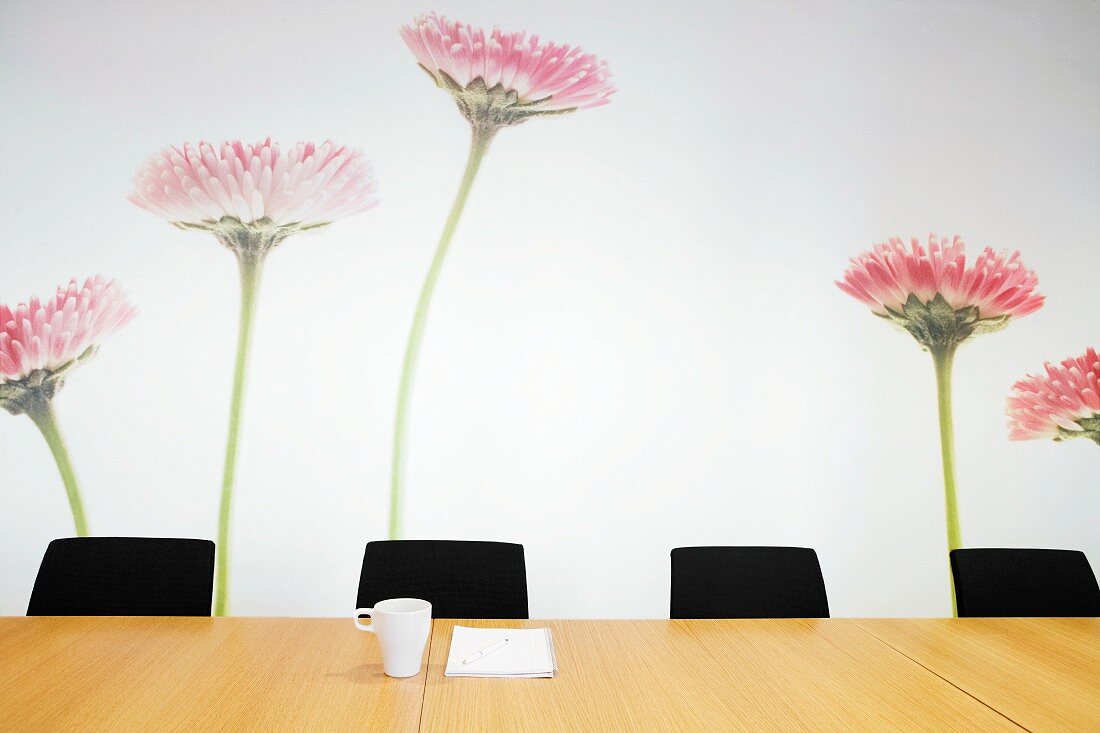 Blumen als Wandmalerei hinter unbesetztem Konferenztisch