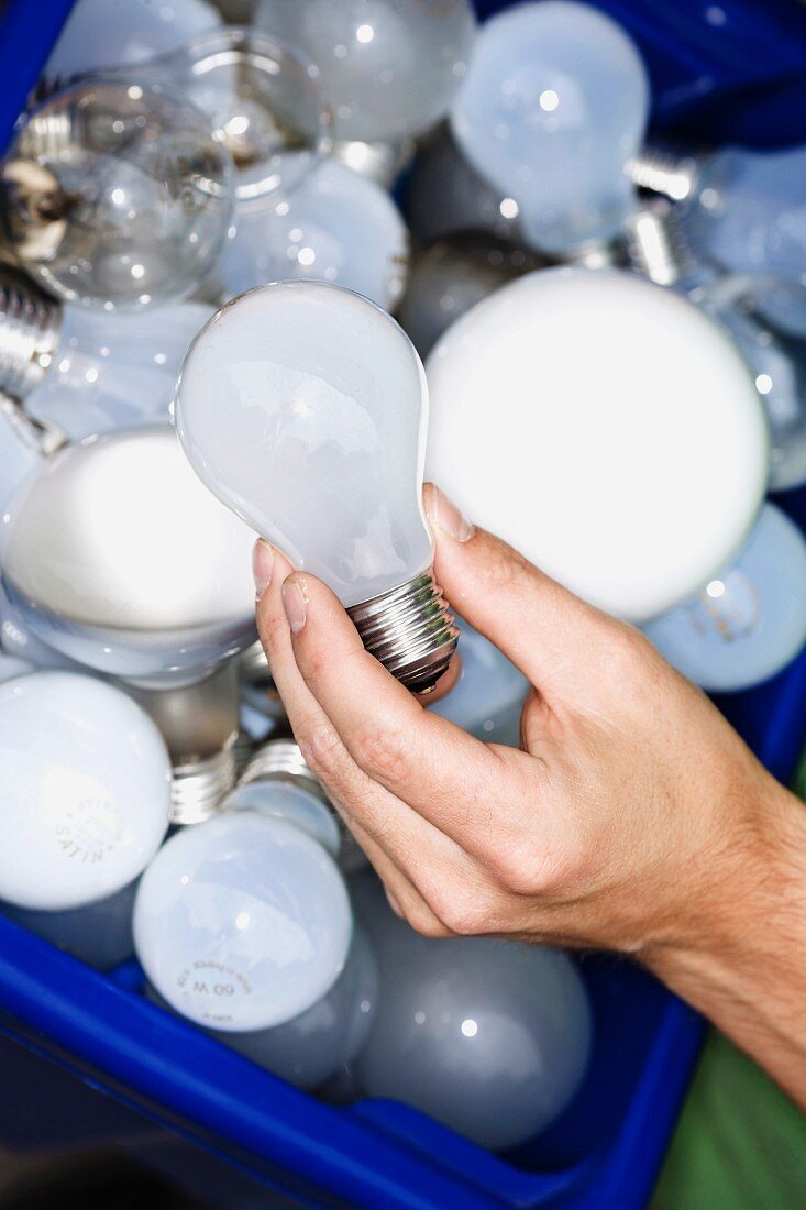 A man holding light bulbs for recycling