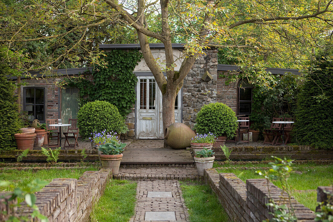 Idyllisches Gartenhäuschen mit Terrasse, Backsteinmäuerchen und Vintage-Atelierstimmung