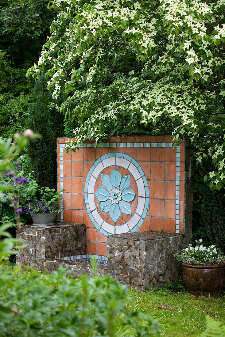 Rückwand eines Natursteinbeckens mit Terracottafliesen und Blütenornament aus glasierten Keramikkacheln