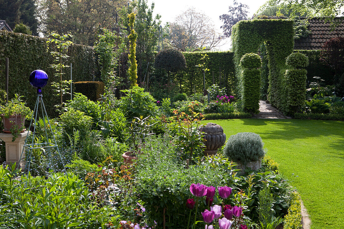 Blühender Garten mit kunstvoll geschnittenen Hecken im englischen Stil