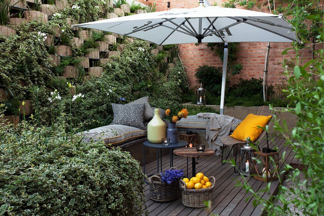 Comfortable seating area on terrace with open parasol surrounded by greenery
