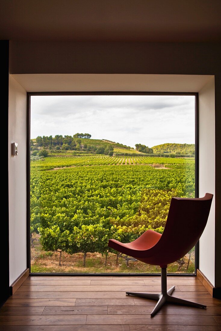 Designer swivel chair in front of picture window in niche with view of French vineyards