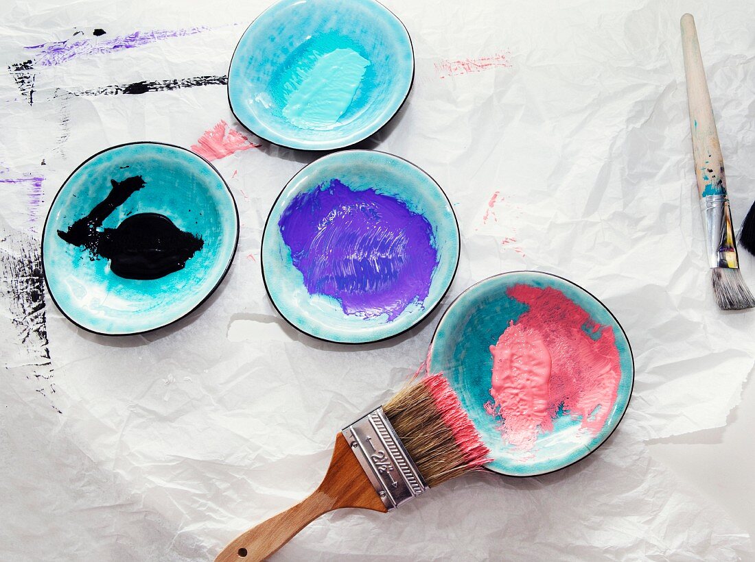 Pinsel und Farbproben auf Keramiktellerchen