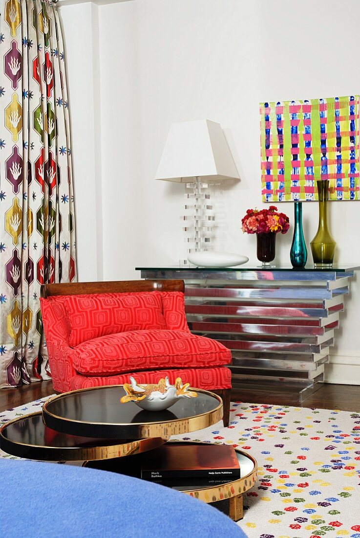 Modern interior with red armchair and chrome console table; modern artwork on wall