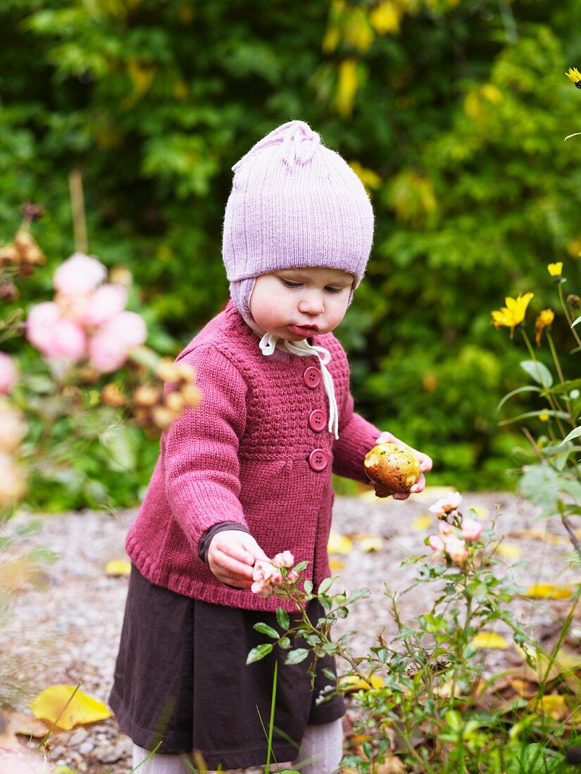 Kleines Mädchen erkundet Blumen im Garten