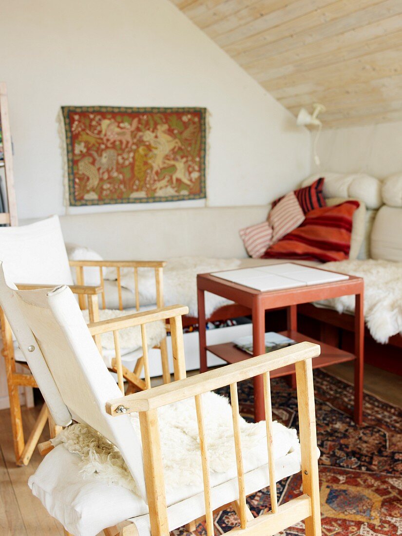 Wohnraum unter Dachschräge mit Sofa, Holzstühlen & Beistelltisch