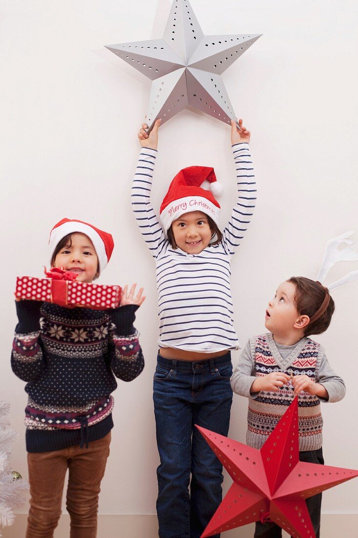 Kinder mit großen Weihnachtssternen und Weihnachtsgeschenk
