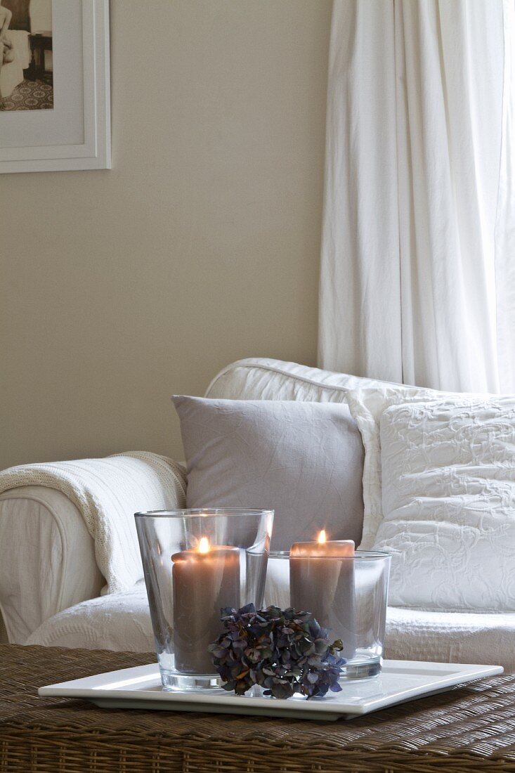 Lit candles on wicker table in front of comfortable sofa