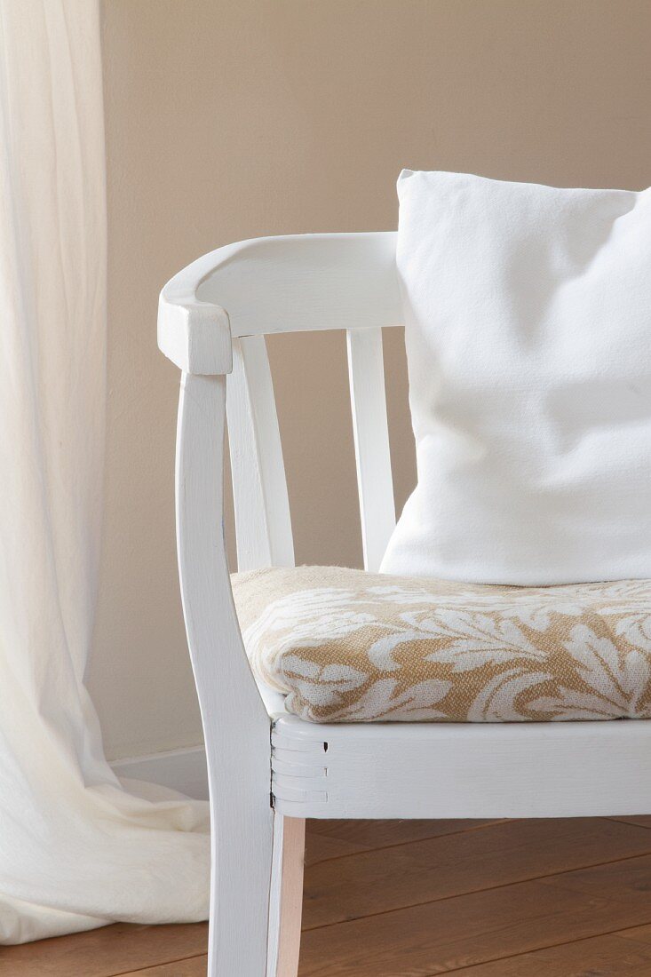 Weisser Armlehnstuhl mit floral gemustertem Sitzkissen