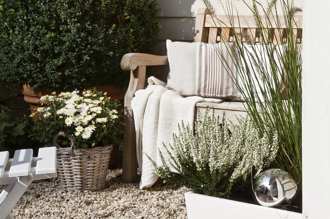 Seating area against house facade with potted plants and rustic wooden bench