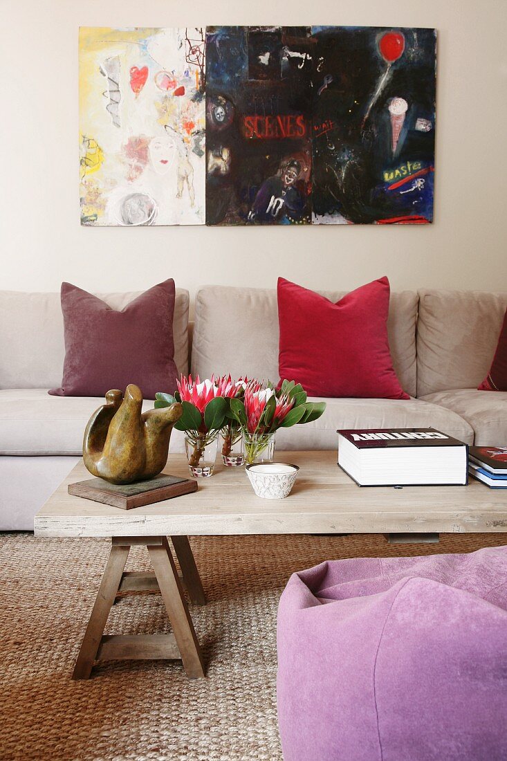 Modern painting in living room with natural textiles and simple wooden coffee table
