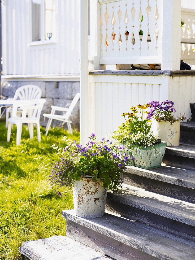 Weisses Holzhaus mit Blumentöpfen auf der Treppe