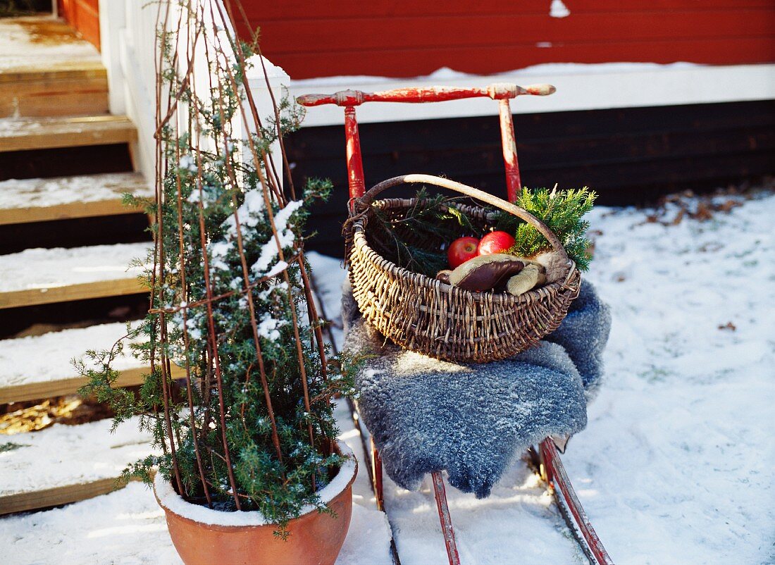 A kick-sled with a basket in front of a house.