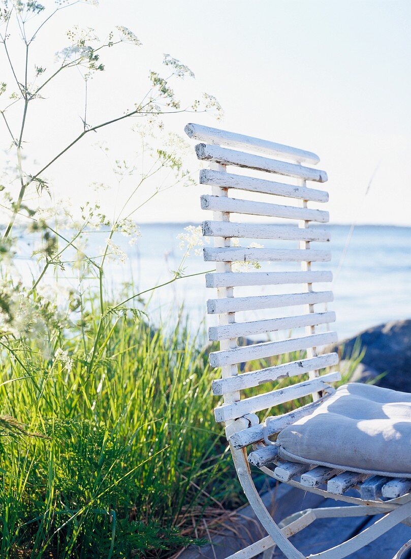 Vintage Stuhl mit Sitzkissen; im Hintergrund das Meer