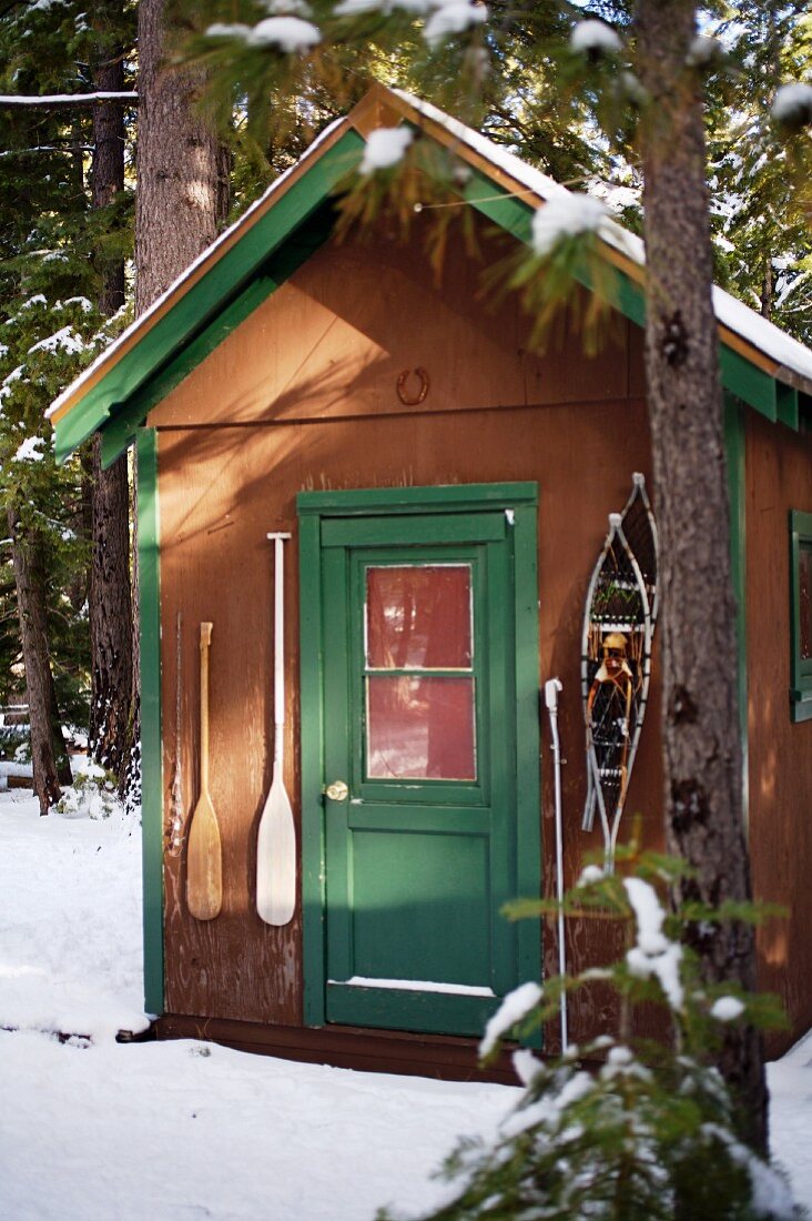 Schutzhütte im Schnee mit Schneeschuhen & Paddeln an Eingangstür hängend