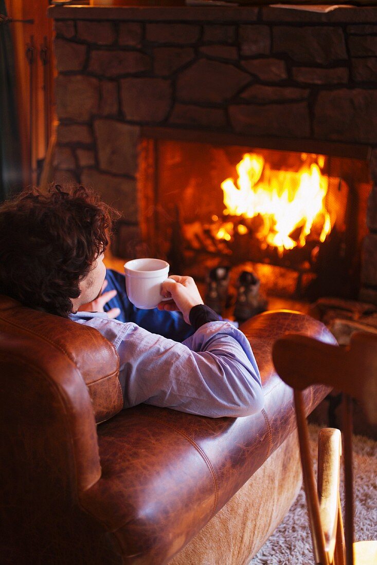 Man next to fire with cup of hot drink