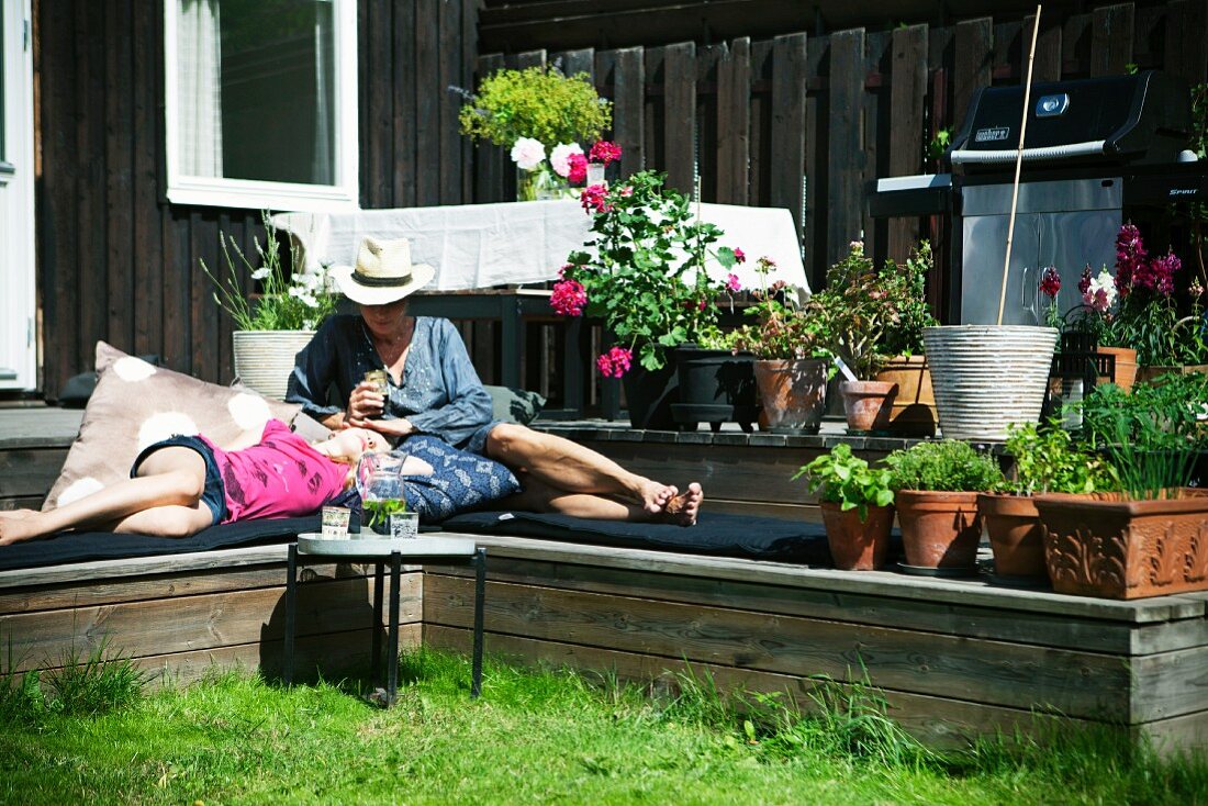 Mutter mit Tochter entspannen auf Terassenstufen im Garten