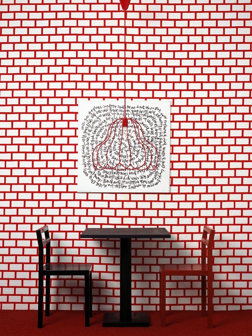 Tisch mit Stühlen vor rot-weiss gemusterter Wand