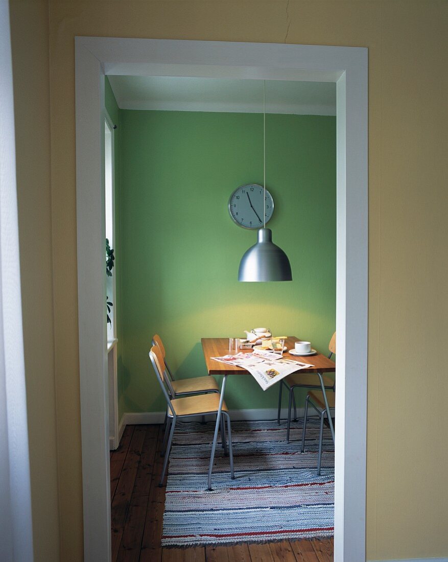 Blick durch Tür auf Esszimmer mit grünen Wänden & Frühstückstisch