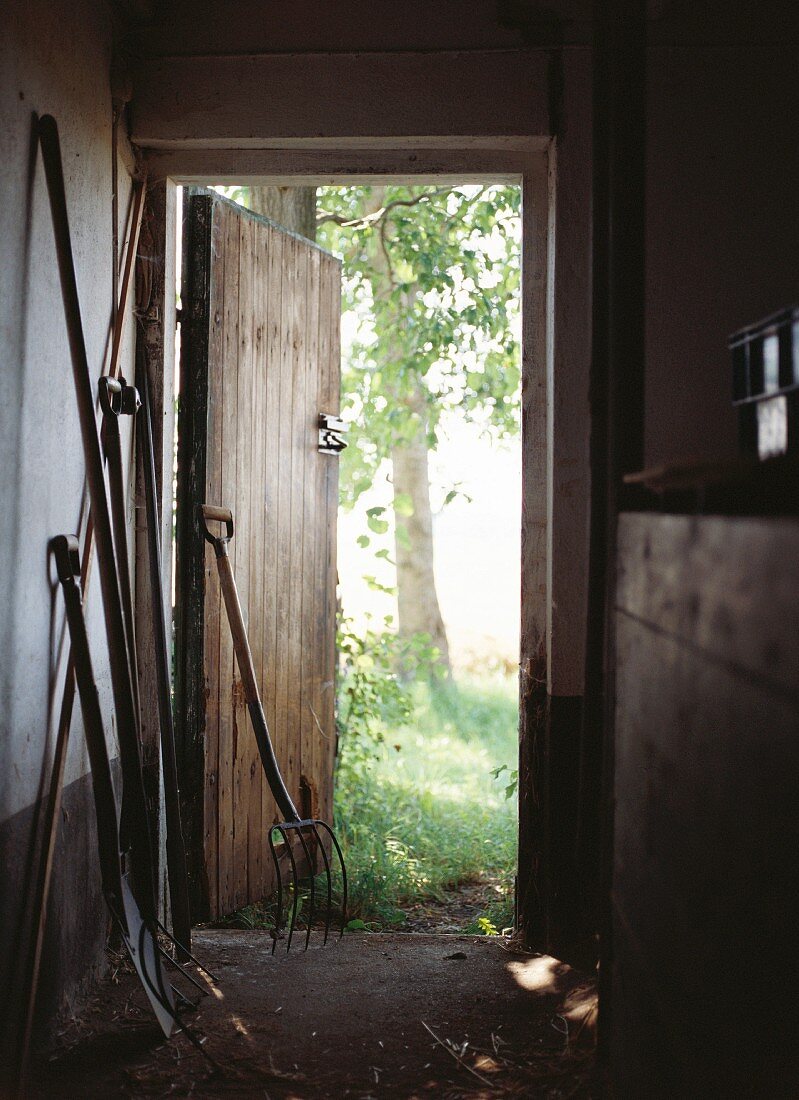 Gartengeräte in Stall mit geöffneter Holztür