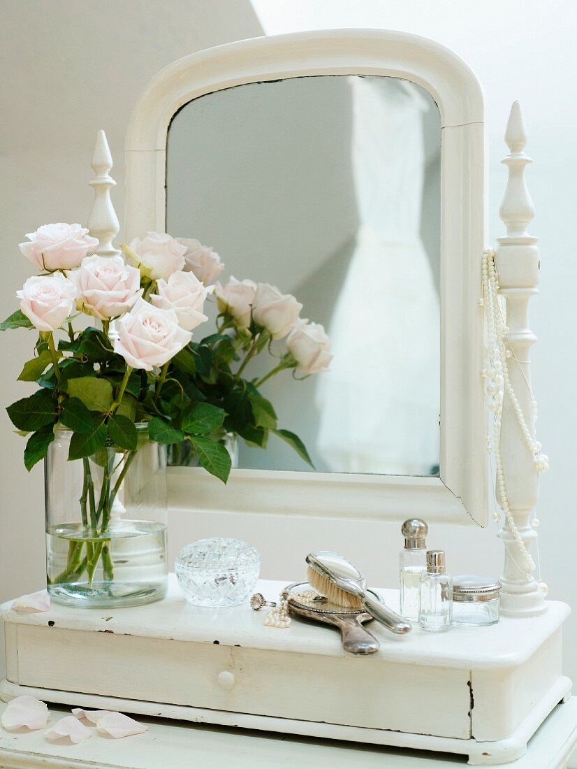 Vase of roses on romantic dressing table with mirror