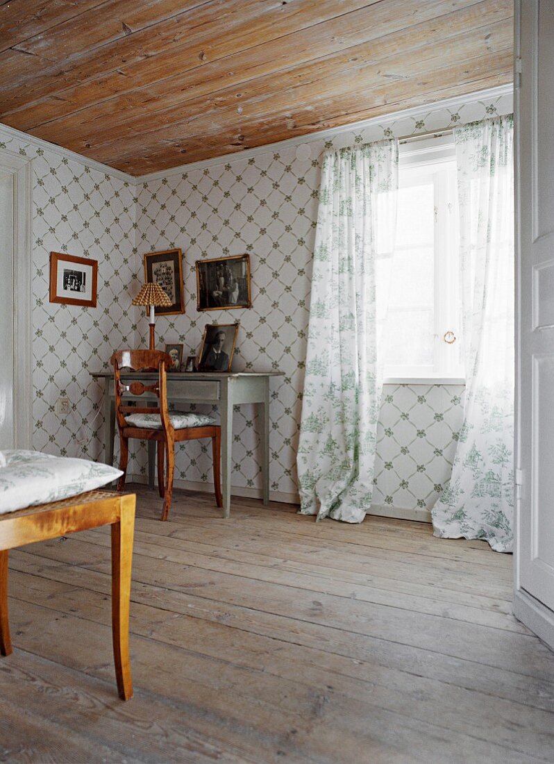 Ahnengalerie an Wand & auf Tisch in Ecke eines Wohnraumes mit Holzdecke & Holzdielenboden