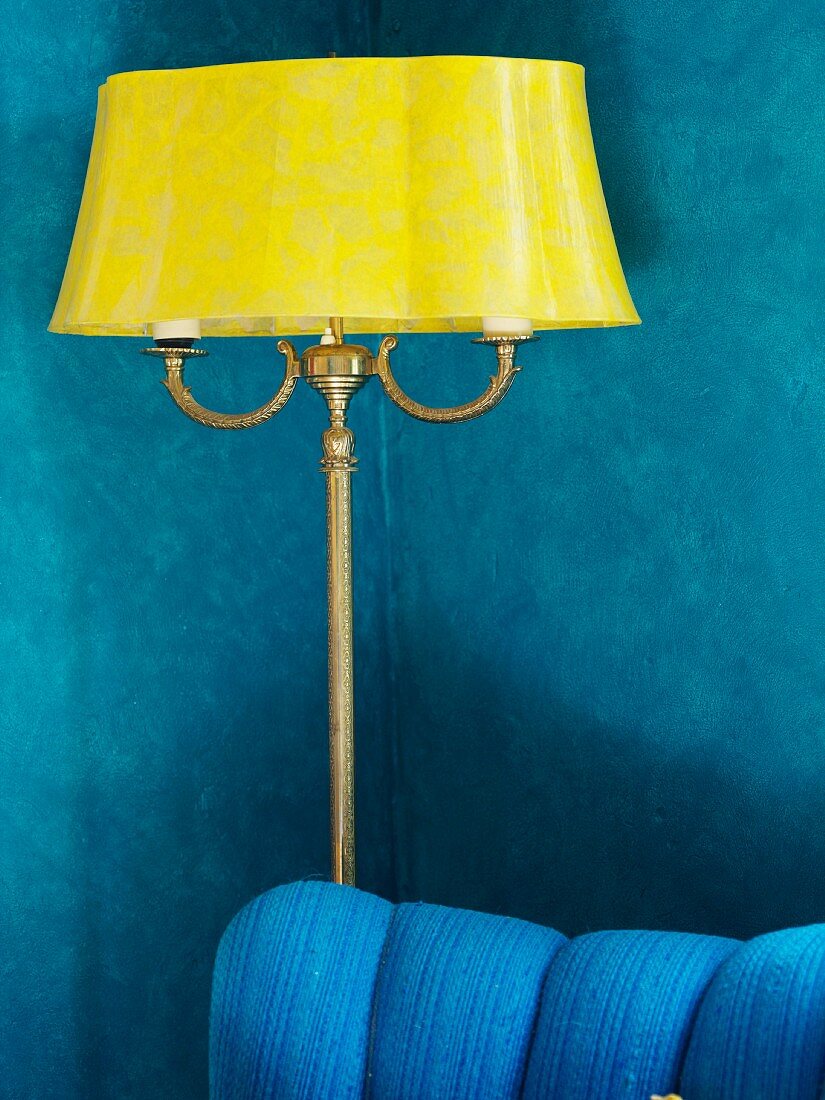 Antike gelbe Stehlampe vor blauer Wohnzimmerwand