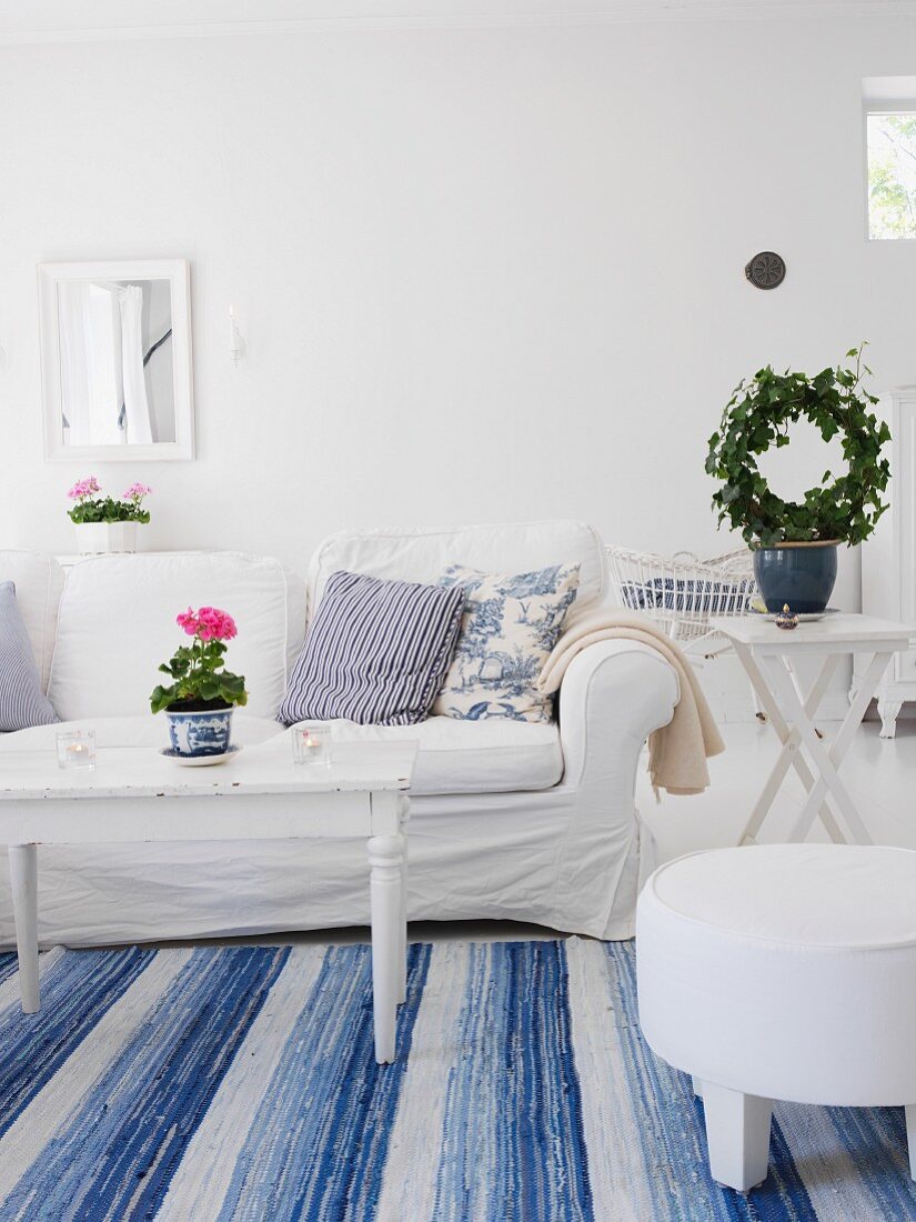 Wohnzimmer in schwedischem Stil mit weißem Sofa & blau-weißem Teppich