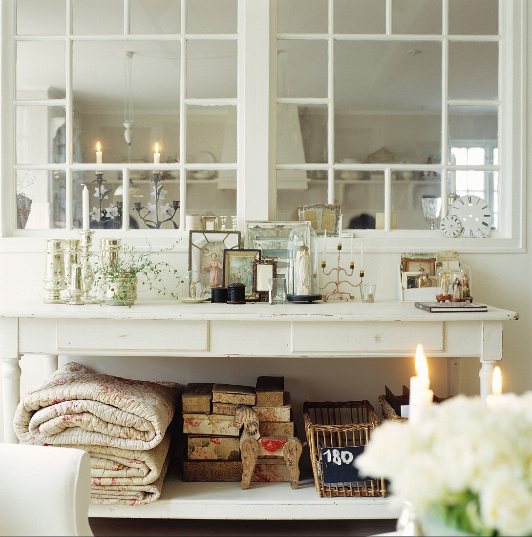 Weiß lackierter Landhaustisch vor Sprossenfenster zur angrenzenden Küche