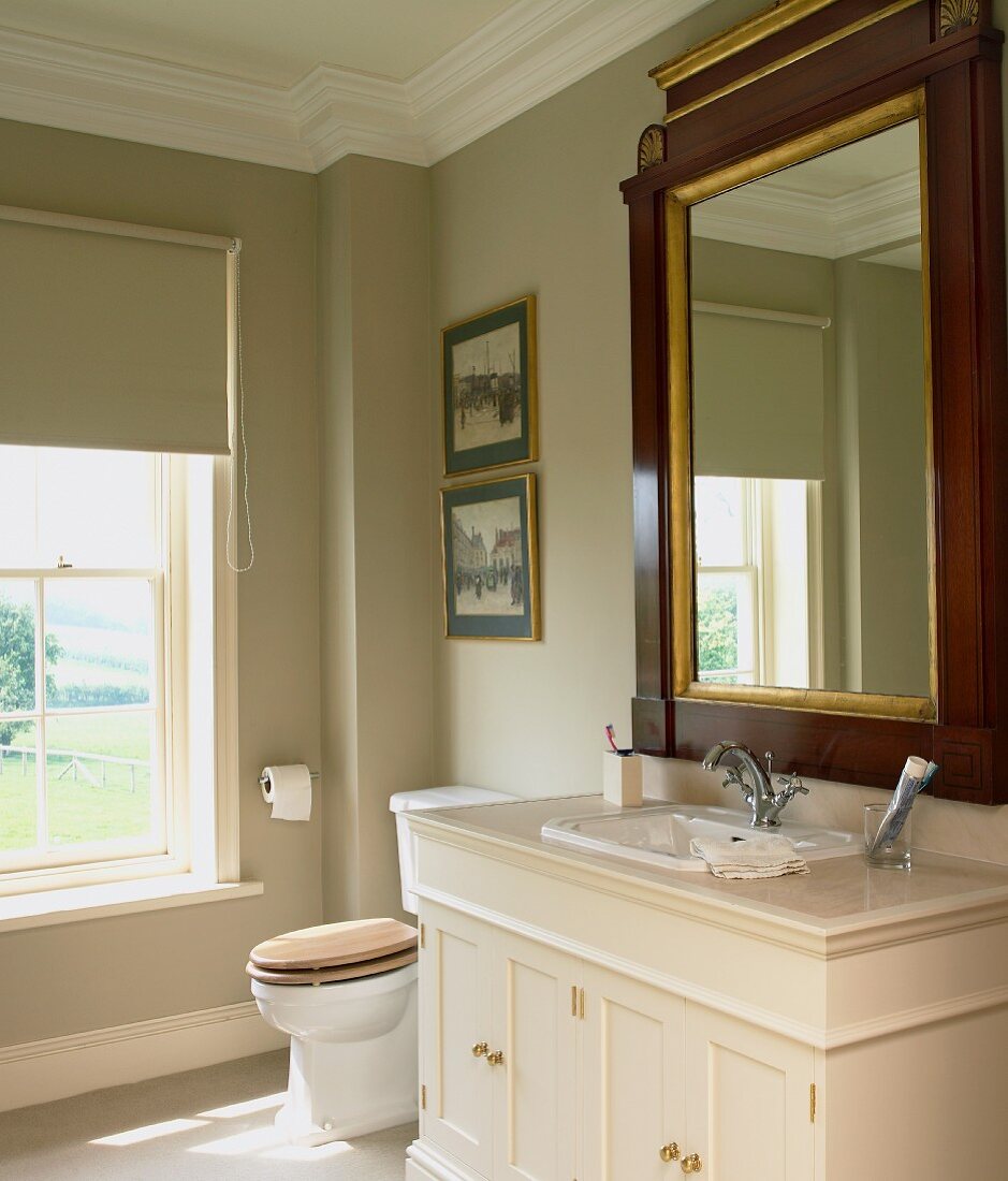Classically elegant bathroom with antique, framed mirror on mushroom grey wall