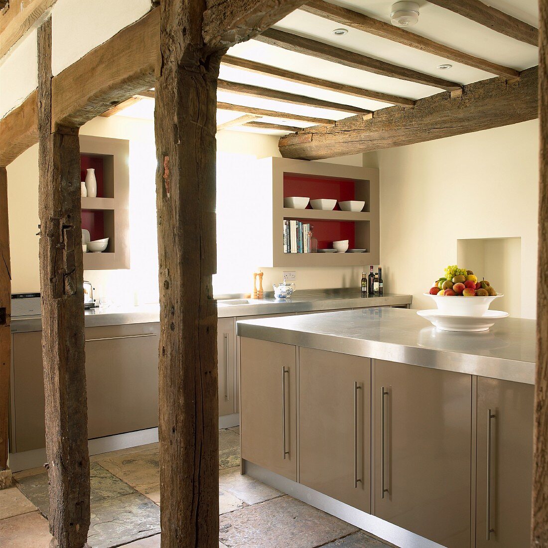 Modern fitted kitchen with island counter in old, half-timbered house with exposed beam structure
